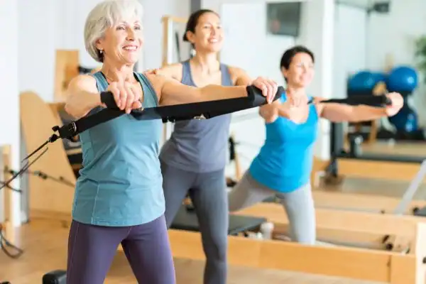 Toning Arms After 60: Empowering Womens Fitness Through Effective Weight Training 2 older woman doing weight training Chippenham and resistance in the gym to tone upper arms